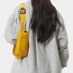 Petit sac banane nylon jaune porté en bandoulière par une femme, vue de dos au style streetwear casual
