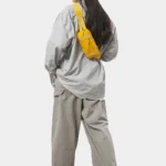 Petit sac banane nylon jaune porté en bandoulière dans le dos par une femme au style streetwear décontracté