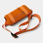Petit sac banane nylon orange posé à plat en vue plongeante, avec sangle réglable à clip plastique