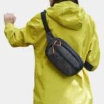 Sac banane nylon ripstop noir quadrillé porté en bandoulière dans le dos par une femme au style sportif outdoor