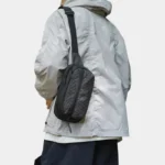 Sac banane nylon ripstop noir quadrillé porté en bandoulière sur l'épaule par un homme au style streetwear