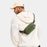 Sac Banane Nylon Imperméable Gorpcore Sac banane nylon vert porté en bandoulière dans le dos par un homme au style gorpcore