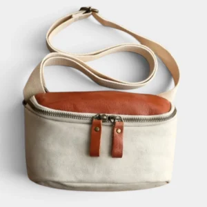 Sac banane en cuir et toile coton écrue posé de face, avec une fermeture zippée métal et sangle ajustable