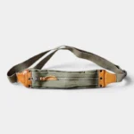 Sac banane en toile kaki et cuir, posé à plat de face avec fermeture zippée et empiècements contrastants