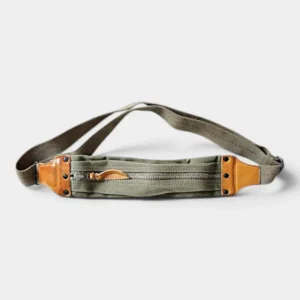 Sac banane en toile kaki et cuir, posé à plat de face avec fermeture zippée et empiècements contrastants