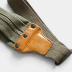 Sac banane kaki en toile et cuir véritable, vu de côté en gros plan sur la sangle avec empiècement riveté