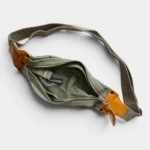 Sac banane en toile kaki et cuir, posé à plat vu de dessus, poche principale ouverte avec crochet métallique intérieur