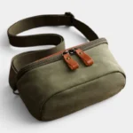 Sac banane en cuir vert kaki au style vintage posé de face, avec sangle épaisse et double tirette en cuir