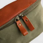 Sac banane toile cuir kaki et marron vu de face gros plan, avec fermeture zippée à tirettes en cuir