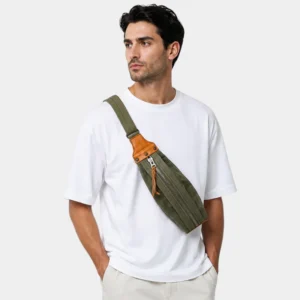 Sac banane kaki en toile coton et cuir, porté en bandoulière par un homme de face au style casual