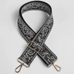 Bandoulière Large Réglable Motif Paisley Bandana Bandoulière large paisley bandana noire et blanche à quincaillerie dorée, posée à plat en croix sur fond neutre