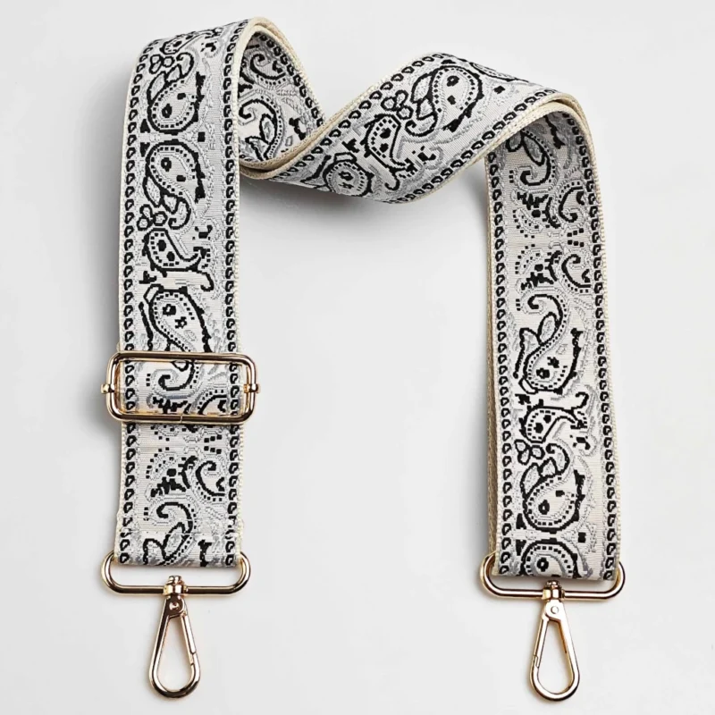 Bandoulière large réglable motif paisley bandana blanc et noir posée à plat avec mousquetons et boucle de réglage dorés