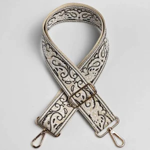 Bandoulière large réglable en polyester jacquard beige crème à motif baroque, posée à plat avec mousquetons et boucle de réglage dorés