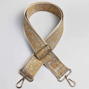 Bandoulière large réglable motif paisley dorée à fond crème avec quincaillerie métal doré, posée à plat vue de dessus
