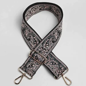 Bandoulière large à motif paisley bandana noir et rose poudré posée à plat, avec mousquetons et boucle de réglage en métal doré