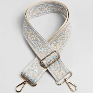Bandoulière large à motif paisley bandana turquoise clair et blanc sur fond beige, avec mousquetons et boucle de réglage dorés, posée à plat