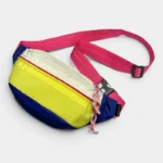 Sac Banane Nylon Ripstop Colorblock Années 90 Sac banane nylon colorblock posé à plat, avec des blocs jaune, bleu marine et blanc et une sangle rose vif
