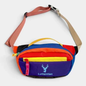 Petit sac banane colorblock en nylon multicolore posé de face, avec sangle bicolore à boucle plastique