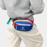 Petit sac banane nylon multicolore porté à la taille de dos, avec zips contrastants bleu, rose et orange