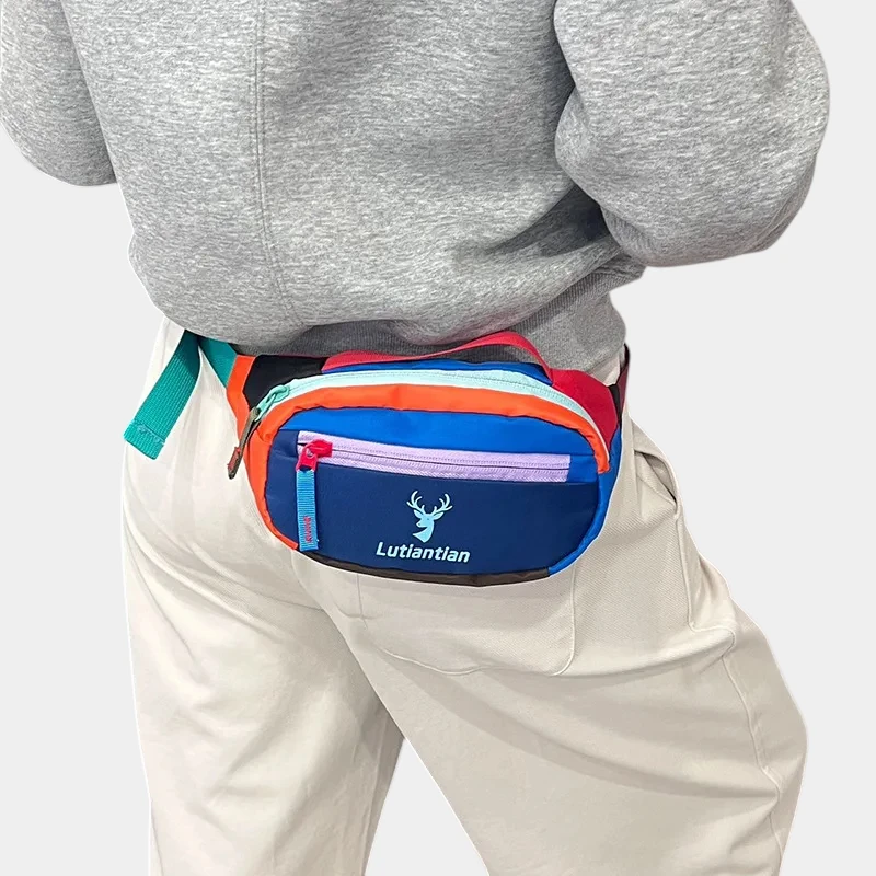 Petit sac banane nylon multicolore porté à la taille de dos, avec zips contrastants bleu, rose et orange