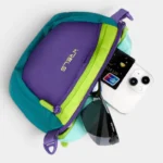 Sac banane nylon colorblock violet, vert et turquoise vu de dessus, poche principale ouverte révélant des lunettes de soleil et un téléphone