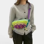 Sac banane multicolore porté en bandoulière par une femme de face au style casual-sport décontracté