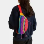 Sac banane multicolore arc-en-ciel porté en bandoulière dans le dos par une femme au style streetwear décontracté