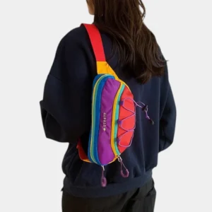 Sac banane multicolore arc-en-ciel porté en bandoulière dans le dos par une femme au style streetwear décontracté