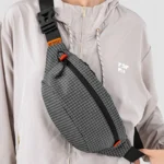 Sac Banane Technique Nylon Ripstop Imperméable Sac banane nylon à carreaux gris porté en bandoulière croisée par une femme au style streetwear urbain-outdoor