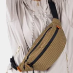 Sac Banane Technique Nylon Ripstop Imperméable Sac banane nylon à carreaux marron clairporté en bandoulière de face, avec fermetures zippées noires et détails orange