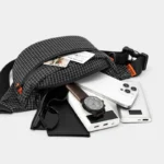 Sac Banane Technique Nylon Ripstop Imperméable Sac banane nylon noir à carreaux, poche principale ouverte révélant un smartphone et une batterie externe