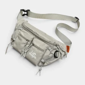 Sac banane nylon ripstop beige clair au style outdoor technique, posé de face avec sangle à clip plastique