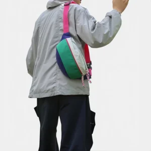 Sac banane nylon colorblock vert, blanc et bleu marine porté en bandoulière dans le dos par un homme au style streetwear