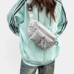 Sac Banane Nylon Ripstop Technique Outdoor Sac banane nylon gris clair porté en bandoulière croisée par une femme au style streetwear décontracté
