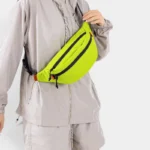 Sac Banane Technique Nylon Ripstop Imperméable Sac banane nylon jaune fluo à carreaux porté en bandoulière par une femme au style streetwear