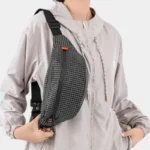 Sac Banane Technique Nylon Ripstop Imperméable Sac banane nylon à carreaux noirs porté en bandoulière par une femme, de face au style sportswear outdoor