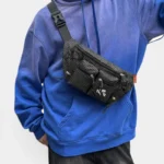 Sac Banane Nylon Ripstop Technique Outdoor Sac banane nylon ripstop noir porté en bandoulière par un homme au style streetwear urbain-outdoor, vue de face