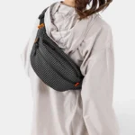Sac Banane Technique Nylon Ripstop Imperméable Sac banane nylon quadrillé noir porté en bandoulière croisée par une femme au style sport-outdoor, de profil