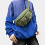 Sac Banane Nylon Ripstop Technique Outdoor Sac banane nylon ripstop vert kaki porté en bandoulière croisée par une personne au style streetwear décontracté