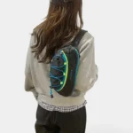 Sac banane outdoor noir porté dans le dos par une femme, avec élastique bleu et vert fluo en façade