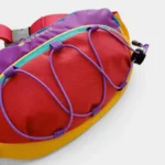 Sac banane outdoor en gros plan, rouge et violet avec des élastiques croisés sur la face avant