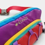 Sac banane multicolore outdoor posé en gros plan, avec zips jaunes et boucle plastique sur sangle rouge
