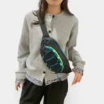 Sac banane outdoor noir porté en bandoulière croisée par une femme au style casual-chic avec des bandes élastiques colorées