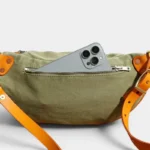 Sac Banane Toile Kaki Militaire Bandoulière Cuir Véritable Sac banane en toile kaki vu de dos, poche avant ouverte avec un iPhone glissé à l'intérieur