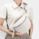 Sac Banane Femme Cuir Grainé Demi-Lune Chic Sac banane en cuir grainé beige porté en bandoulière croisée par une femme au style chic décontracté