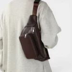 Sac Banane Homme Cuir Grainé Minimaliste Sac banane en cuir grainé marron porté en bandoulière par un homme au style casual-chic, vue de face