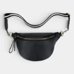 Sac Banane Femme Cuir Grainé Demi-Lune Chic Sac banane cuir grainé noir posé à plat de face, avec sangle rayée et fermeture éclair dorée
