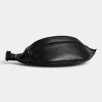 Sac Banane Homme Cuir Grainé Demi-Lune Sac banane en cuir grainé noir posé sur le côté, avec une fermeture zippée argentée en façade