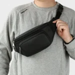 Sac Banane Homme Cuir Grainé Minimaliste Sac banane cuir grainé noir porté en bandoulière croisée par un homme de face au style casual-chic