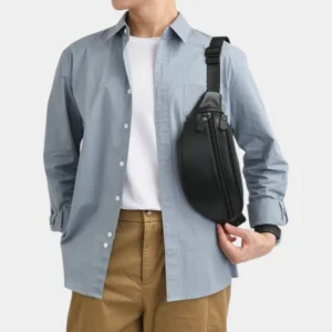 Sac banane en cuir grainé noir porté en bandoulière par un homme de face au style casual chic